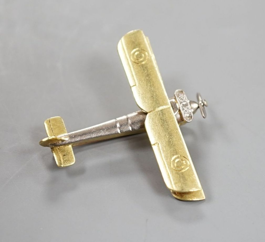 An early 20th century 15ct, white metal and three stone diamond set bi-plane brooch, with revolving propeller, 31mm, gross weight 4.6 grams.